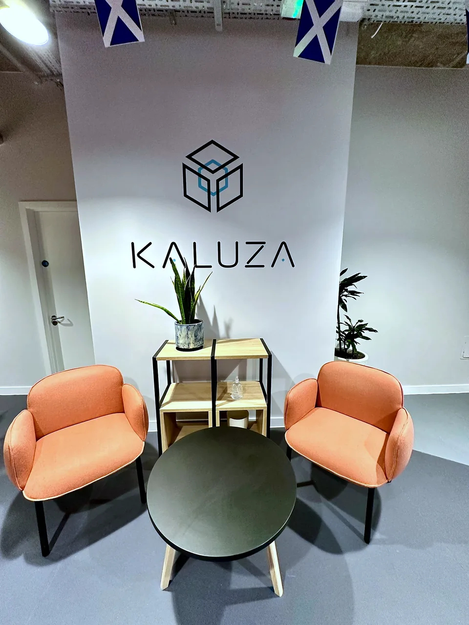 The reception at Kaluza, Edinburgh, with brand signage, orange armchairs and a planted display.
