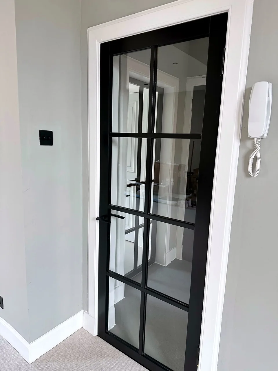 A black framed glazed door and entry intercom at Broughton Street Lane.