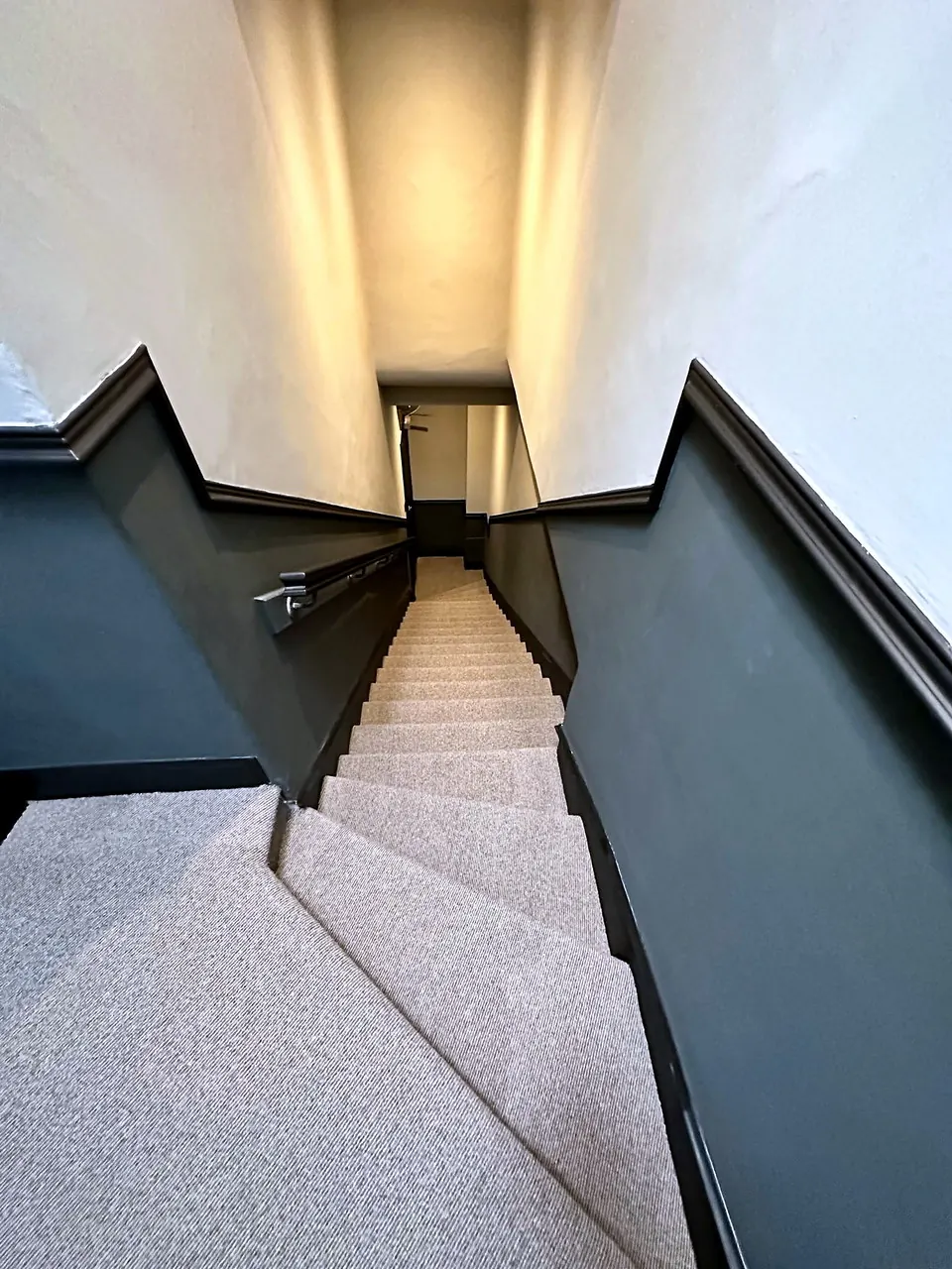 The stairwell at Broughton Street Lane, with navy panelling and a carpeted stair.