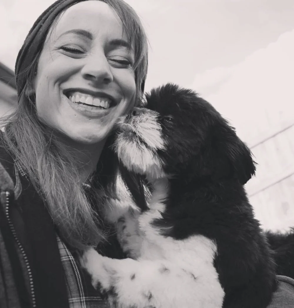 Jenna, founder of The Canine Enrichment Co., relaxing outdoors with a happy young dog