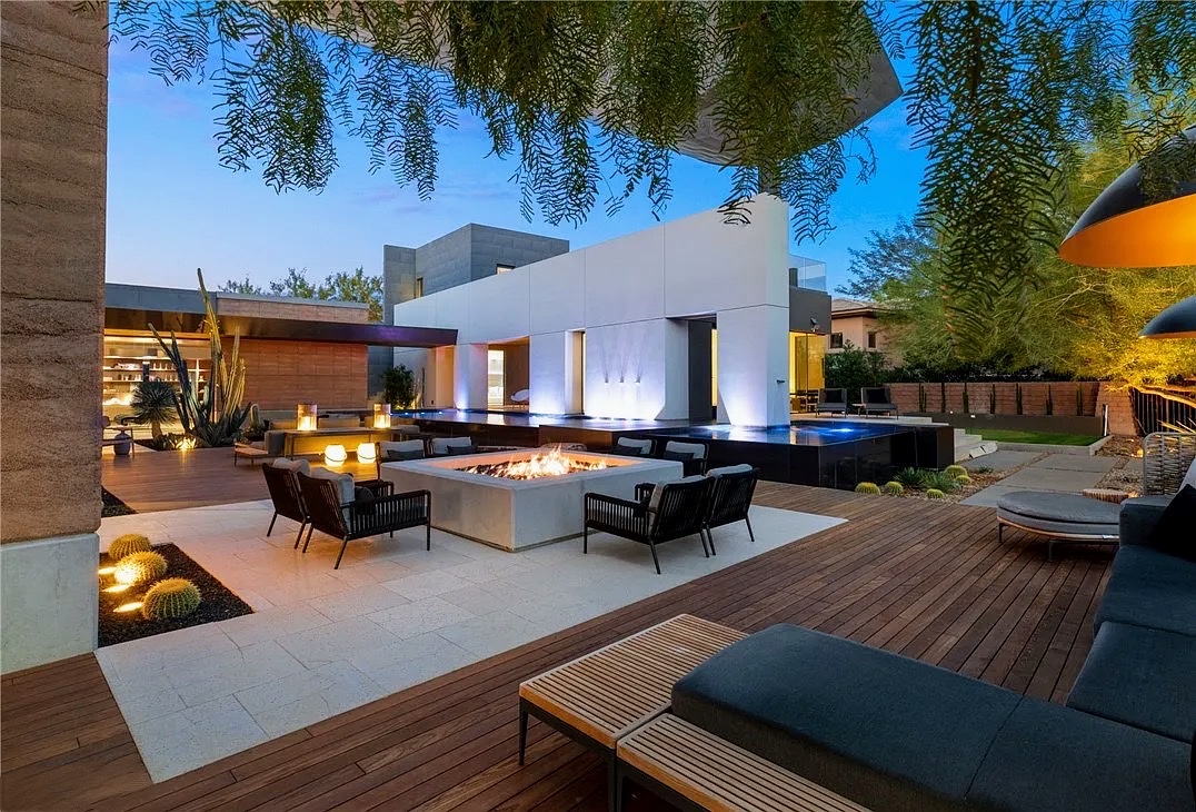 Twilight backyard lounge with fire pit and uplit modern facade