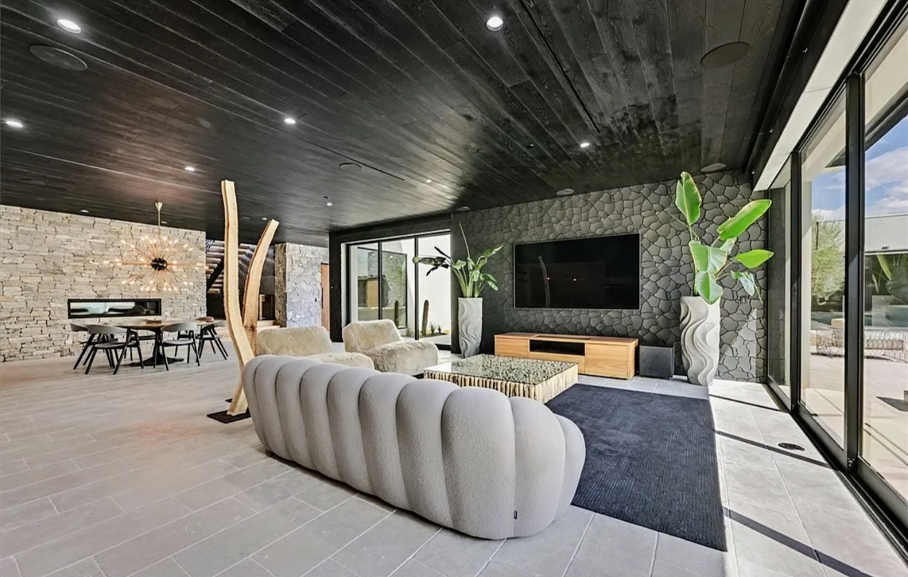 Living room with charcoal wood ceiling, stone feature wall and curved sofa