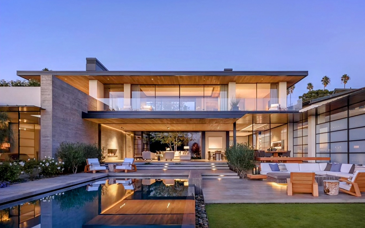 Wood and glass modern estate at dusk with reflecting pool and covered lounge