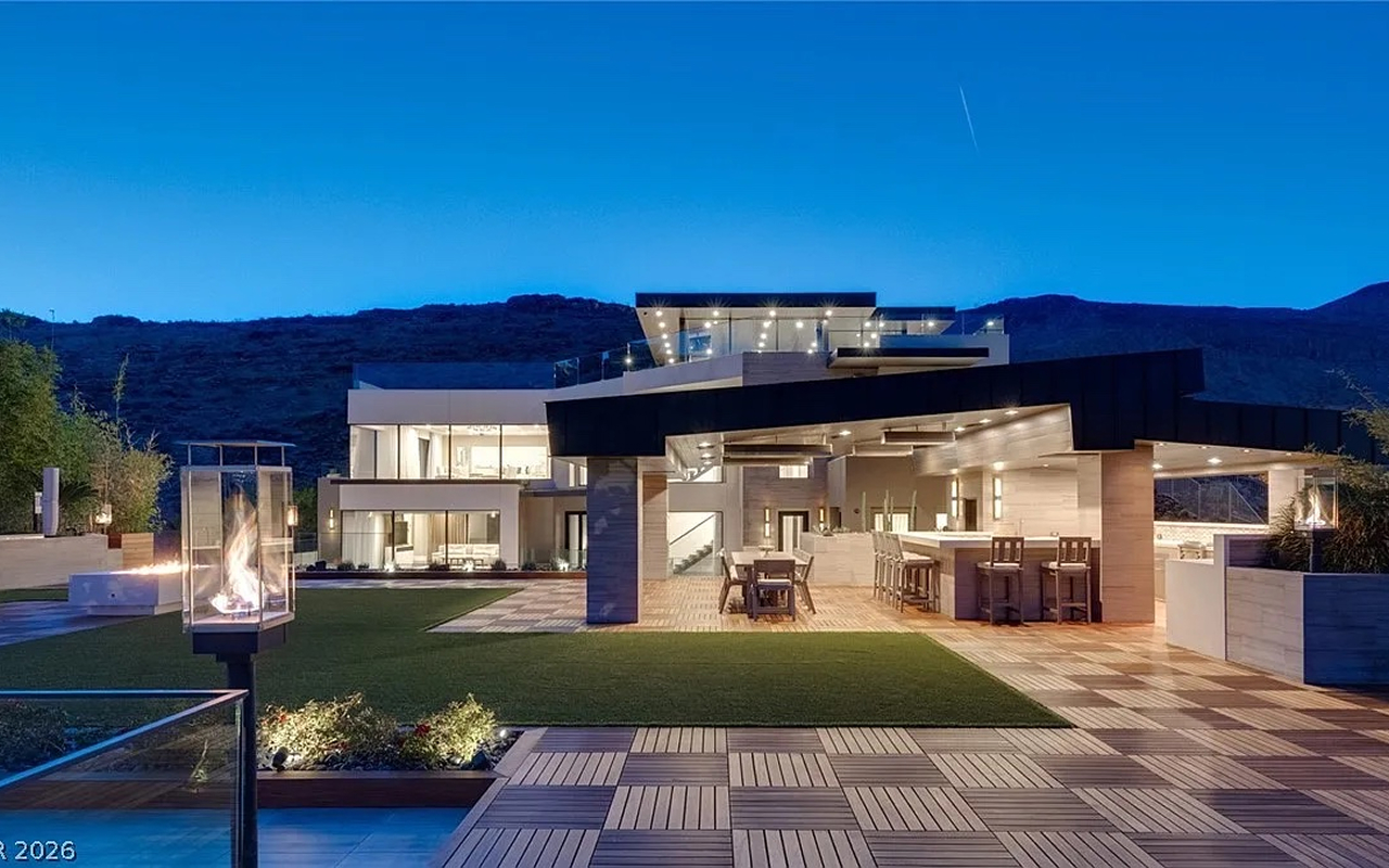 Hillside contemporary estate at blue hour with covered outdoor kitchen and fire features