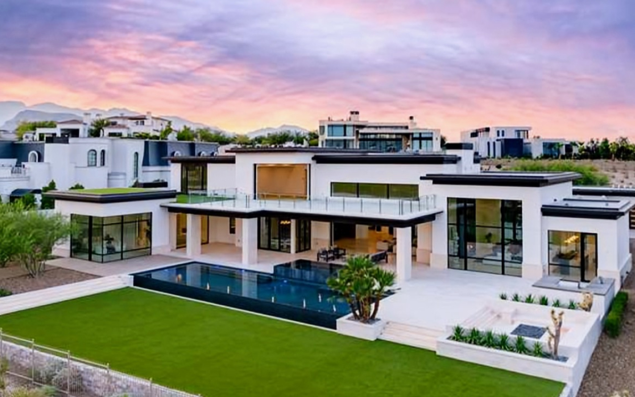 White contemporary estate at sunset with lap pool and manicured lawn