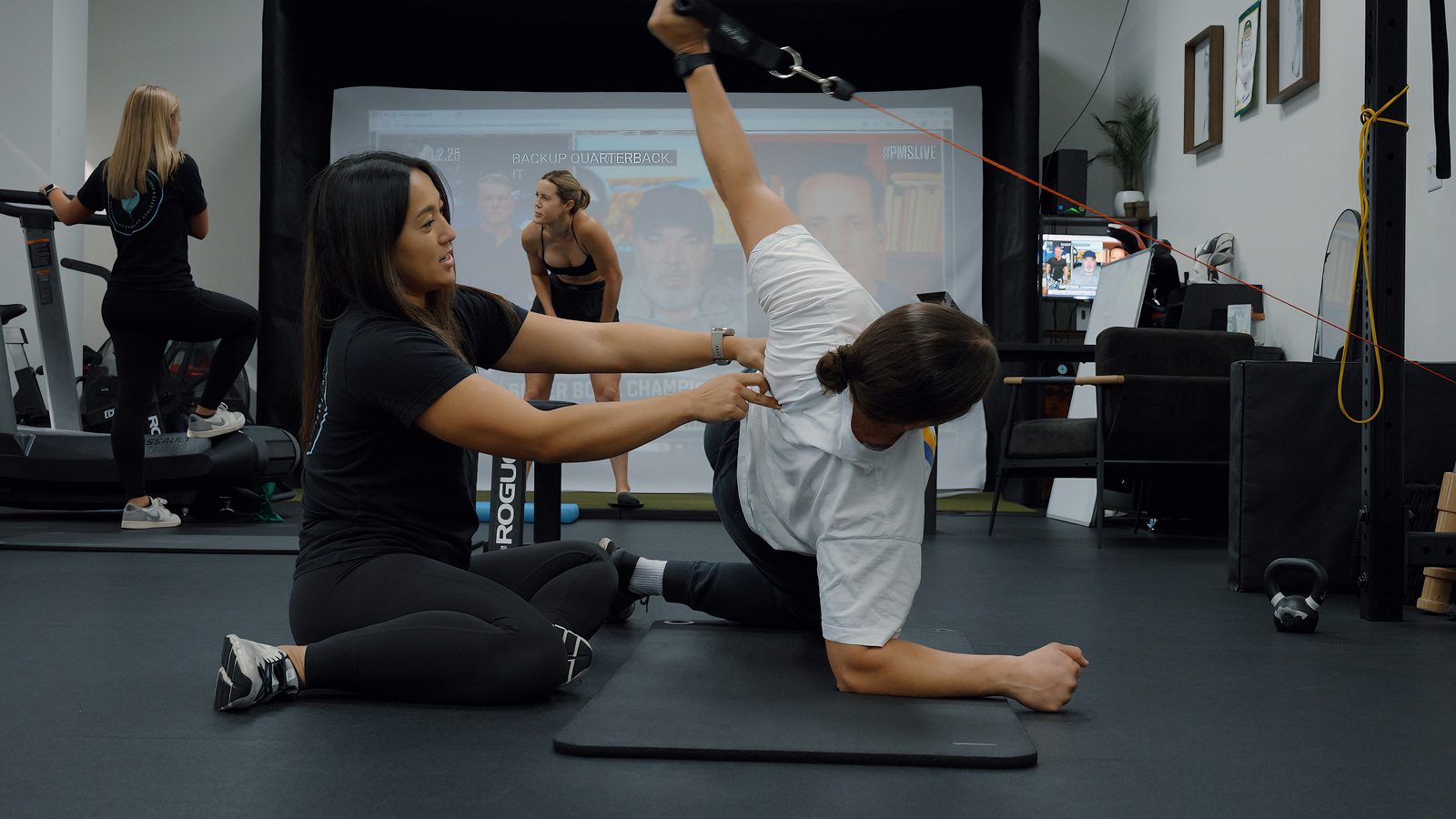 PT guiding athlete through corrective exercise
