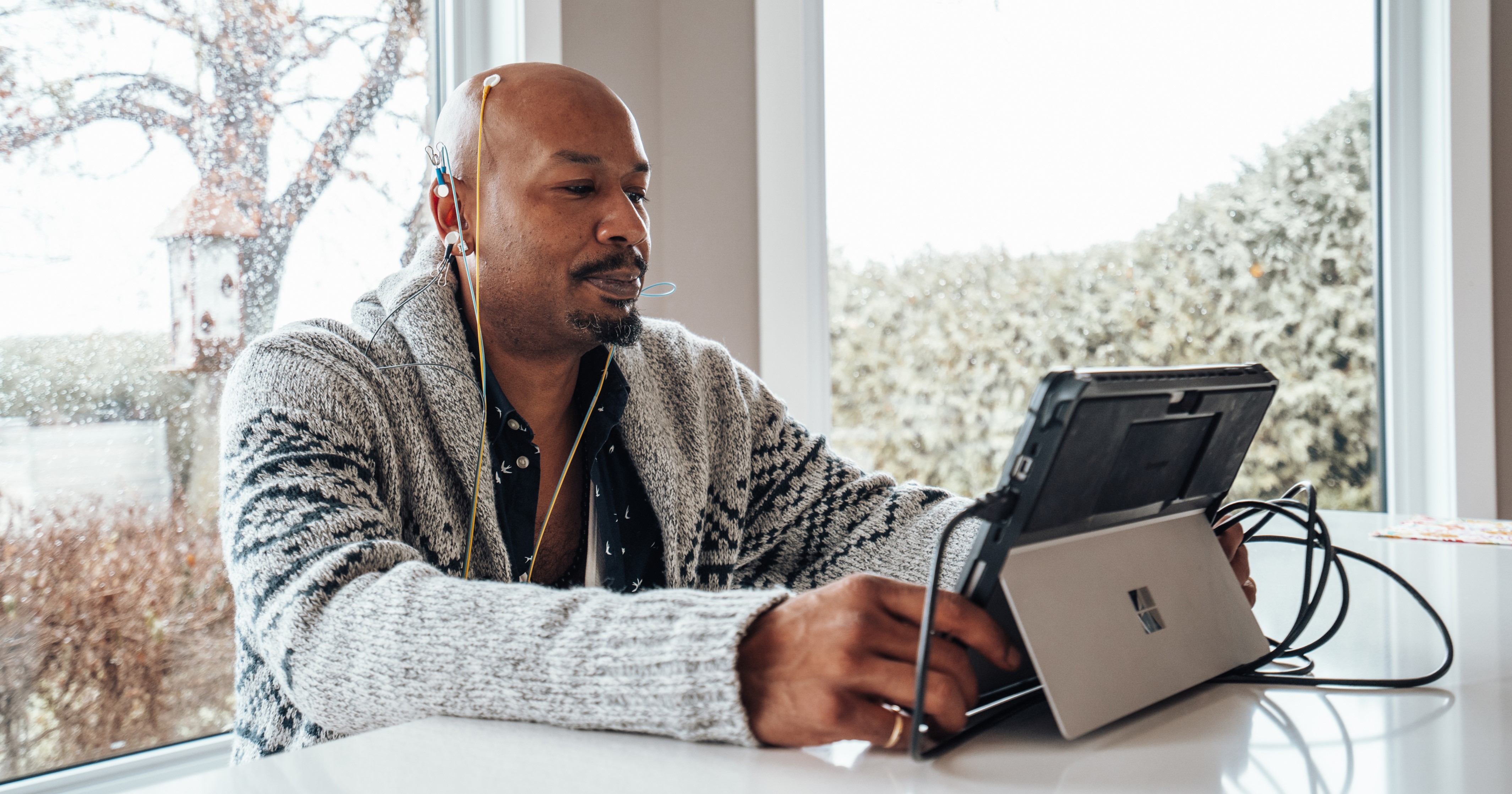 Man in a focused NeurOptimal® neurofeedback session, calm and engaged, natural light from window