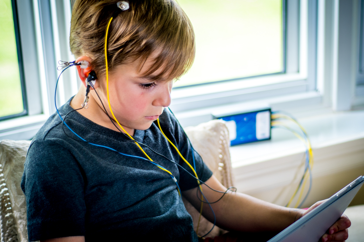 Child completing a NeurOptimal® neurofeedback session in a comfortable home setting near a window