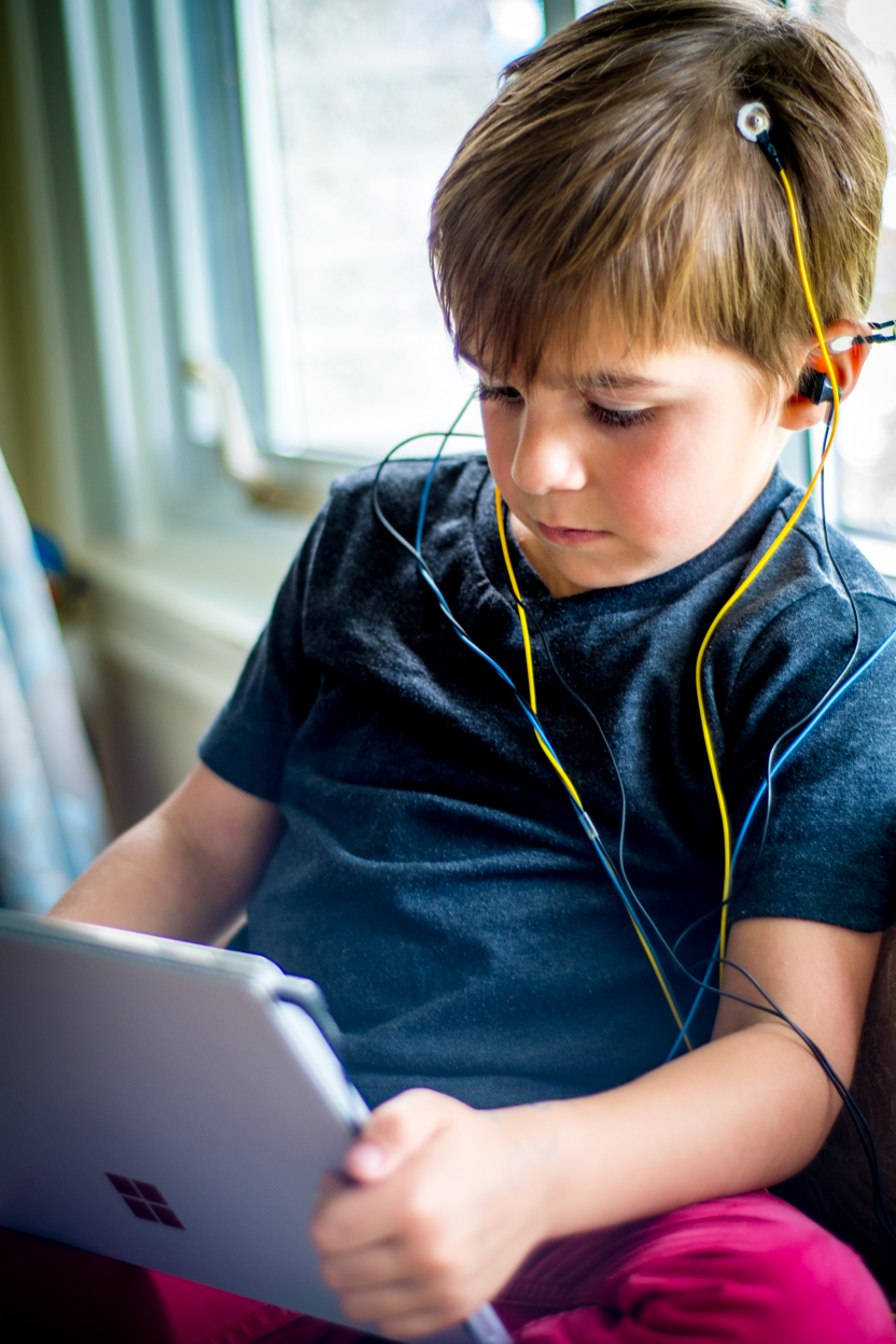 Young boy doing a NeurOptimal® neurofeedback brain training session at home, calm and focused