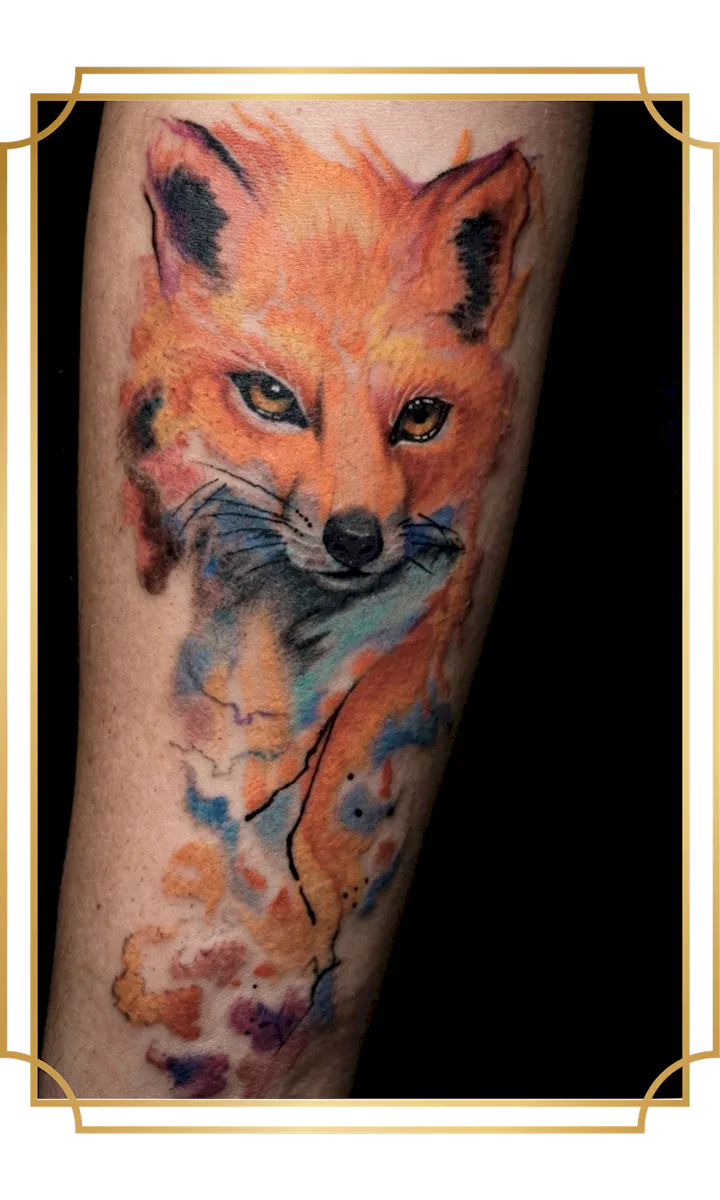 Watercolor fox portrait tattoo with vivid orange fur, blue shadows and loose paint-splash details by San Marcos artist Alek the Saint