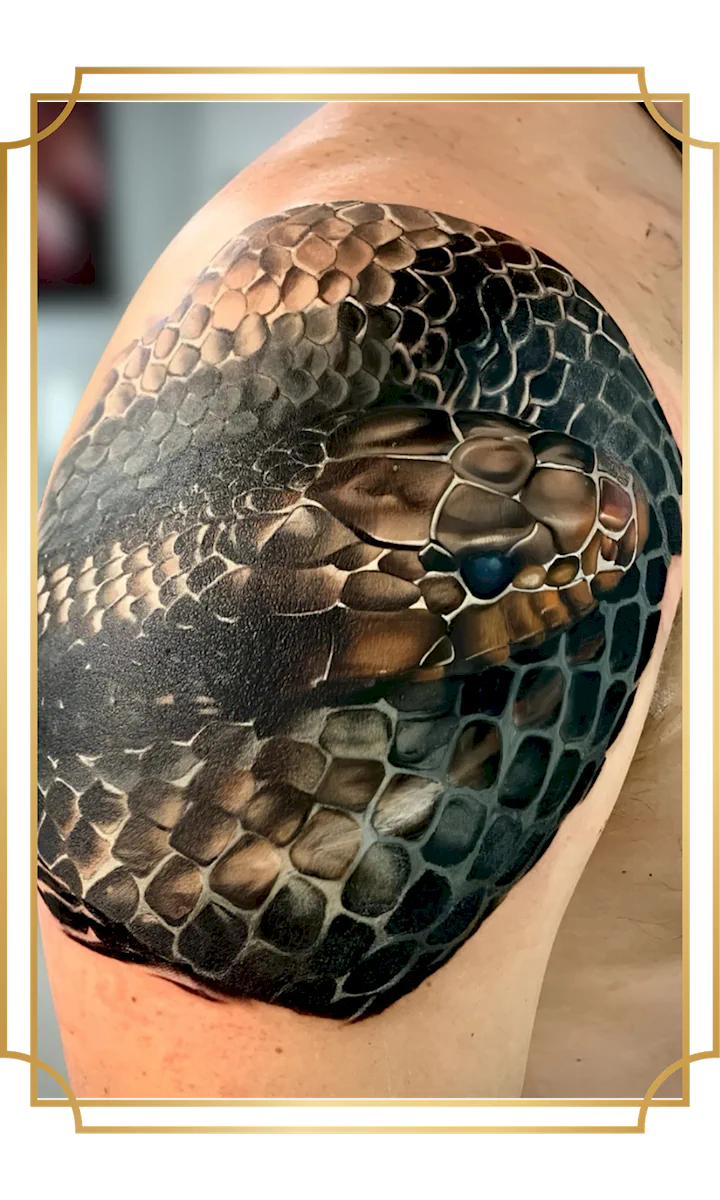 Realistic coiled snake cover-up tattoo wrapping the shoulder and upper arm with detailed scales