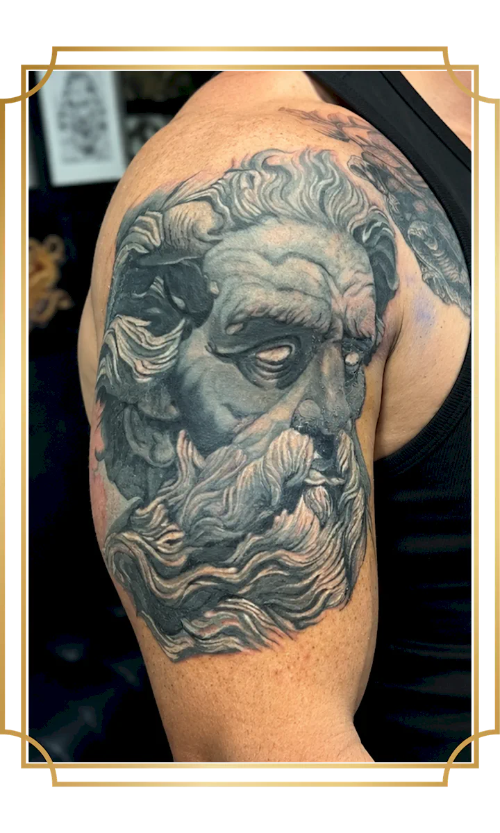 Black and gray realism tattoo of a bearded classical figure on the upper arm