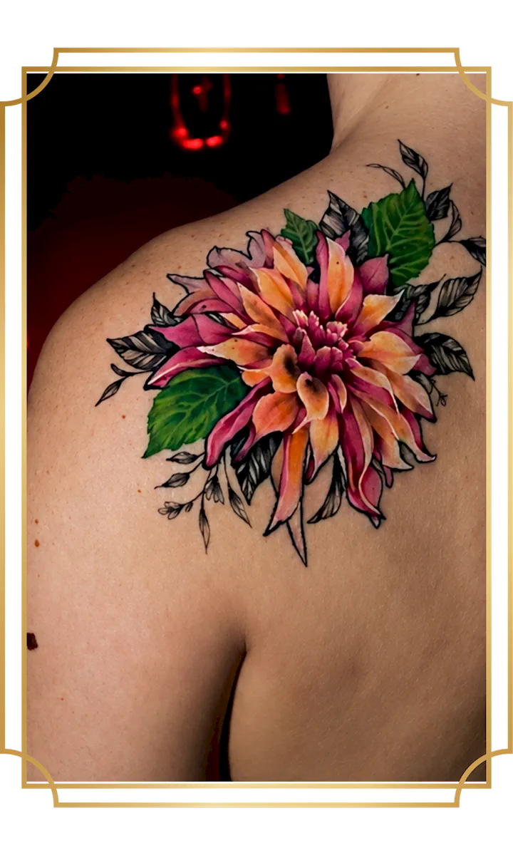 Vibrant color dahlia shoulder tattoo with pink and orange petals, saturated green leaves and black illustrative foliage, created in San Marcos