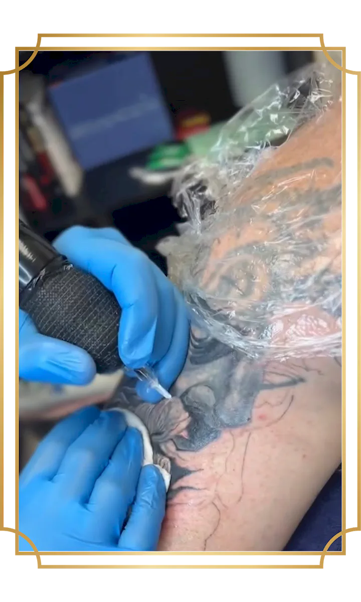 Tattoo artist working on a black and gray bearded face tattoo during a tattoo session