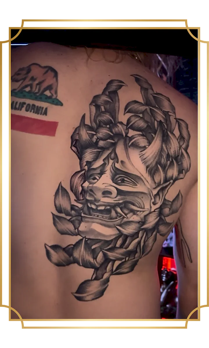 Black and gray oni mask tattoo inside a chrysanthemum on the back