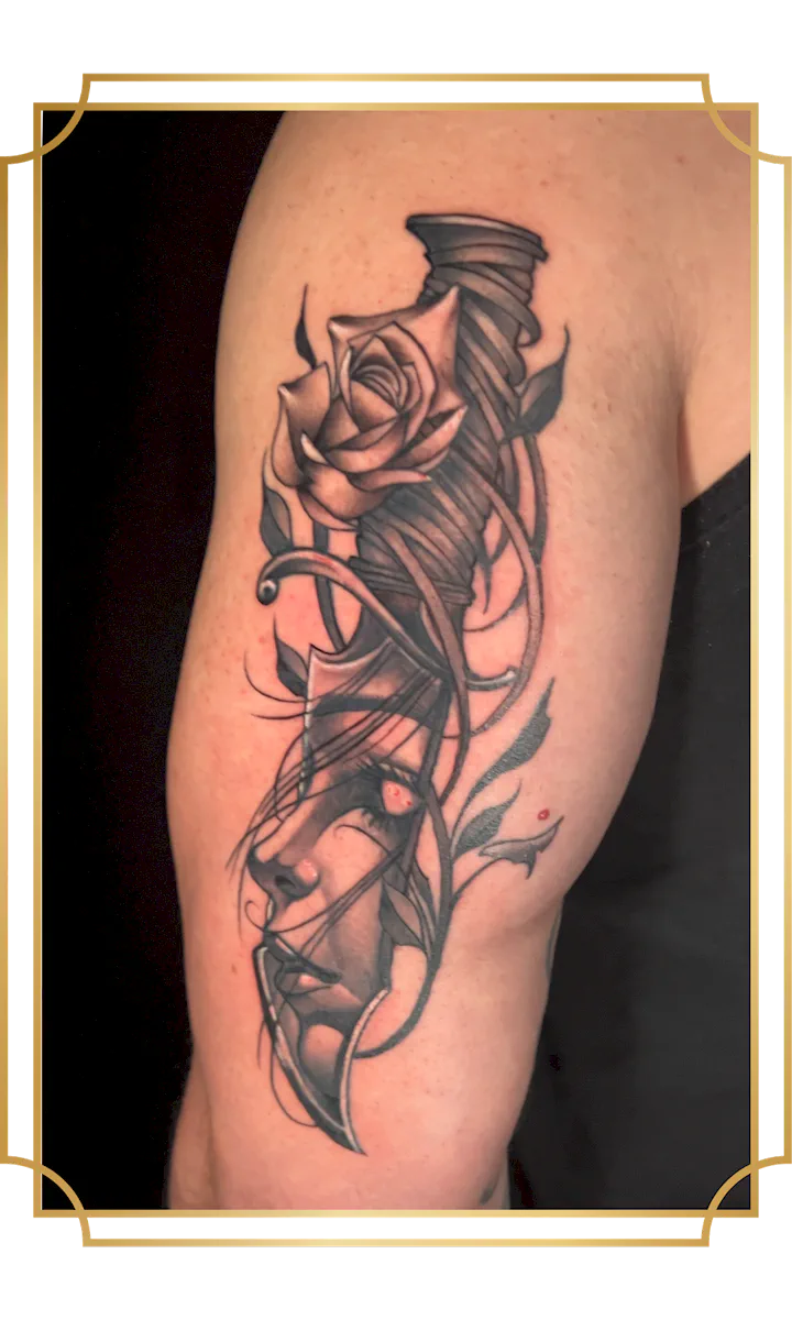 Black and gray surreal woman's face tattoo with rose and geometric linework on the upper arm