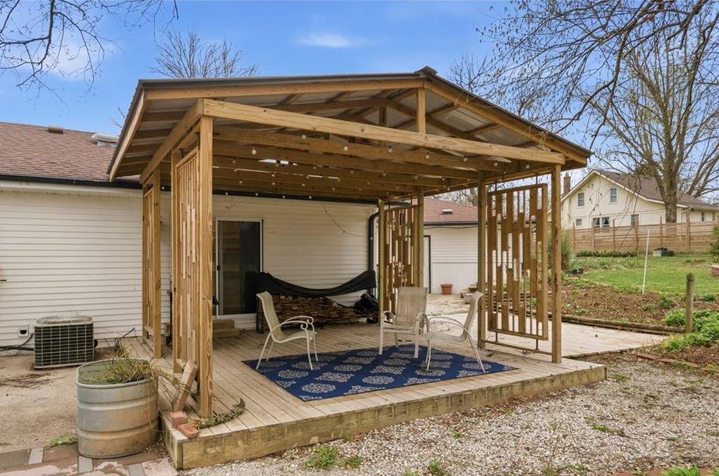 Covered outdoor deck with seating and string lights at ranch home for sale Excelsior Springs MO with acreage and resort style backyard near Kansas City