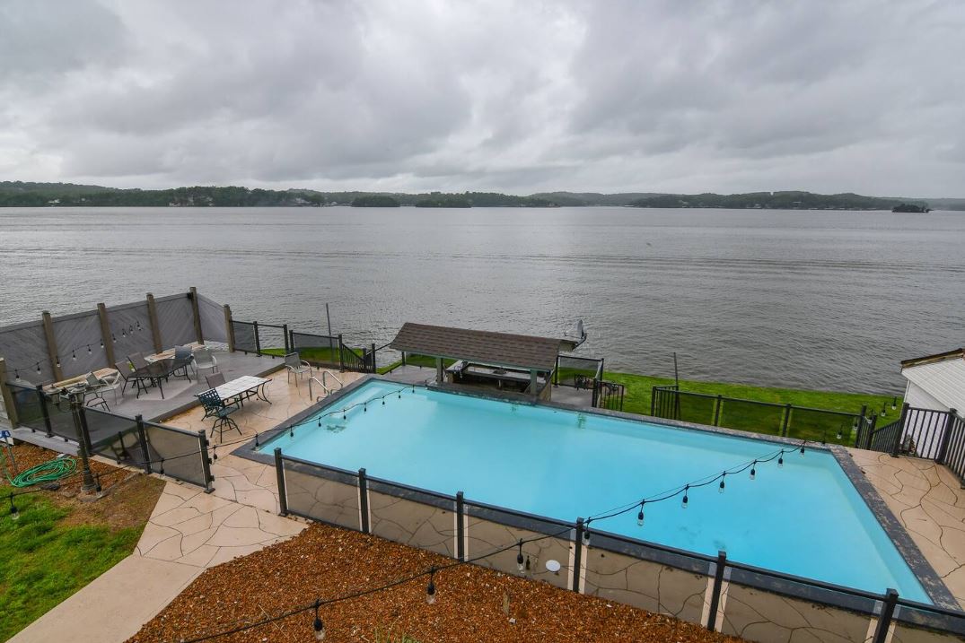 Aerial view of saltwater pool with glass fencing and string lights overlooking the Lake of the Ozarks main channel at the Luxury Lake House vacation rental with swim-up bar near Shady Gators in Lake Ozark Missouri Aerial view of saltwater pool with glass fencing and string lights overlooking the Lake of the Ozarks main channel at the Luxury Lake House vacation rental with swim-up bar near Shady Gators in Lake Ozark Missouri