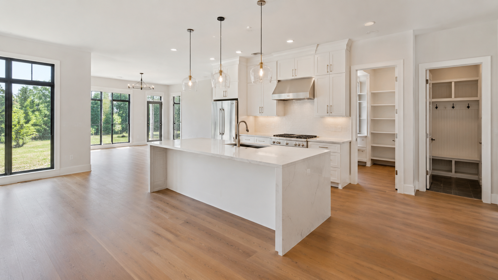 Bright, newly built open-concept home featuring a large quartz kitchen island, walk-in pantry, mudroom, wood floors, and oversized windows. Bright, newly built open-concept home featuring a large quartz kitchen island, walk-in pantry, mudroom, wood floors, and oversized windows.