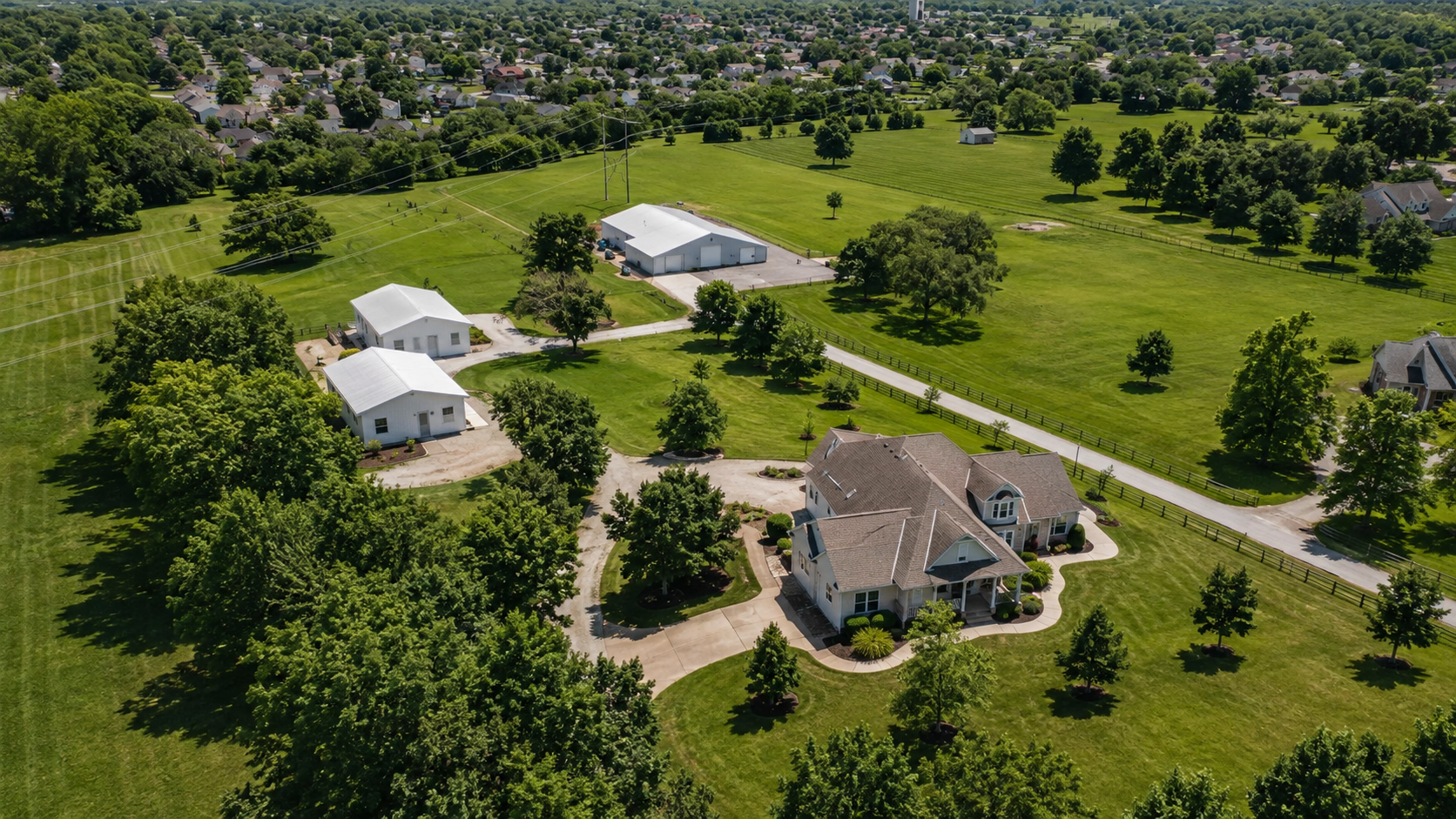 Aerial view of a Greenwood, Missouri acreage property with a main residence, three rental outbuildings and separate drives and parking areas.