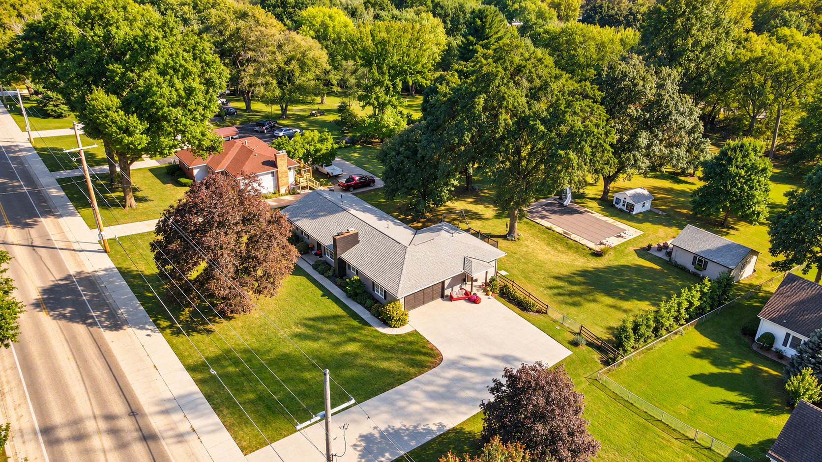 Aerial view of 10035 W 55th Street in Merriam KS, featuring a ranch home, covered pool, and detached workshop on 1.42 acres.