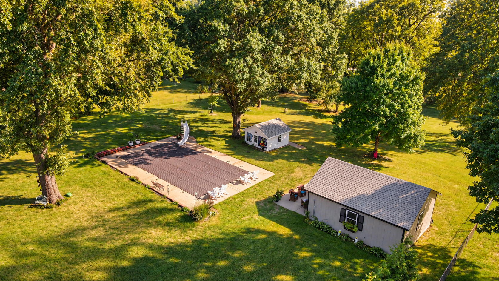 Covered in-ground pool, detached workshop, and spacious backyard with mature trees at a Merriam KS ranch home.