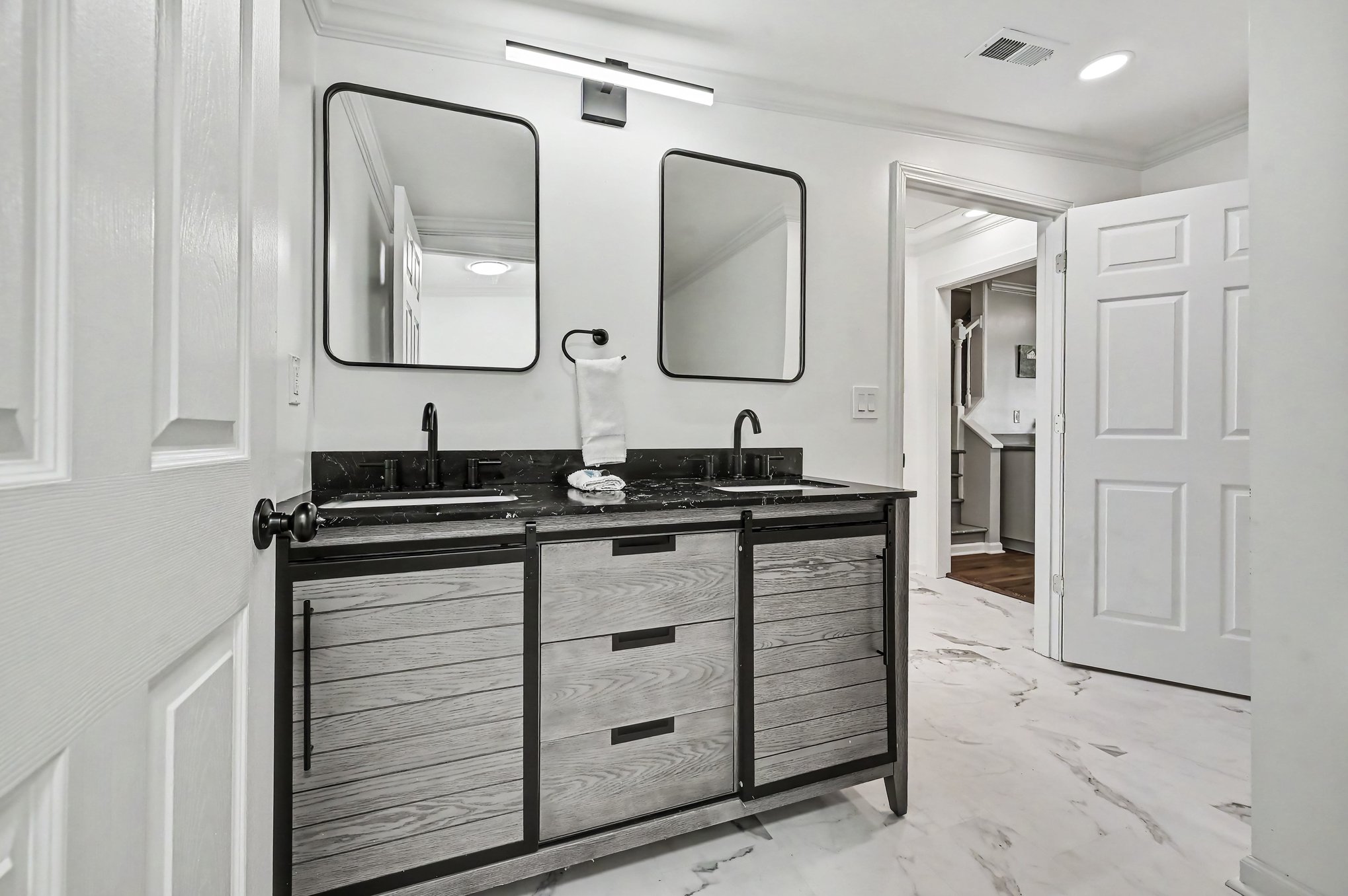 Double vanity with black quartz top, matte black fixtures and marble-look tile floor