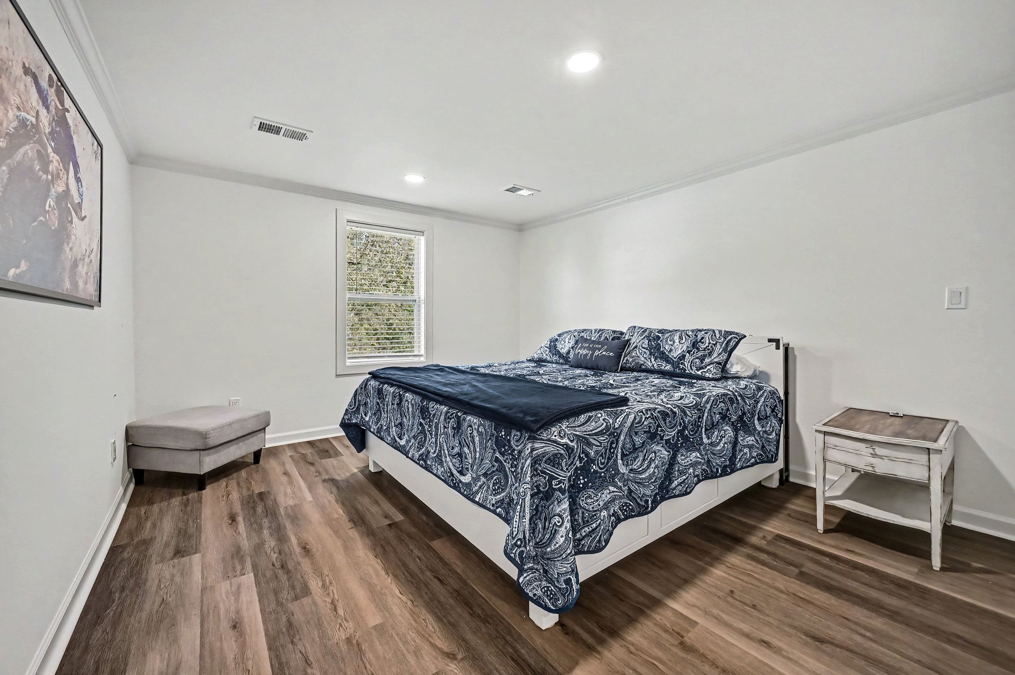 Primary bedroom with king bed, navy paisley bedding, nightstand and window