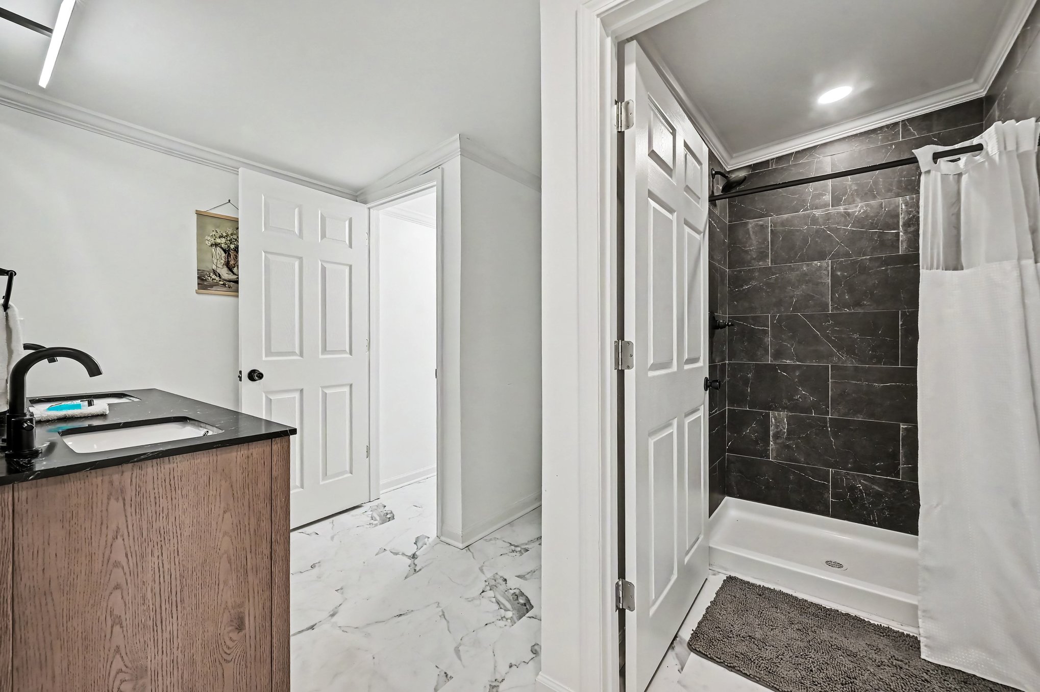 Bath with charcoal marble-look tile shower and wood vanity