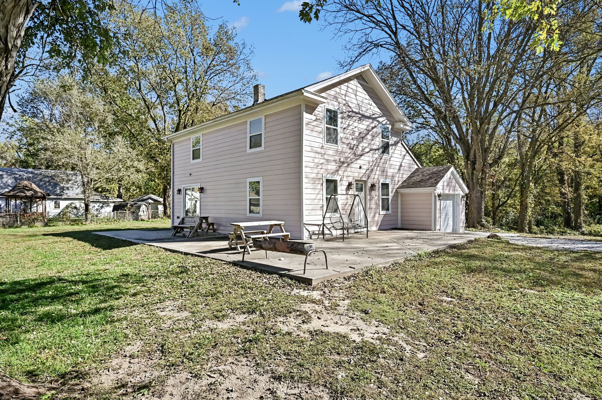 Exterior with wraparound concrete patio, picnic tables and porch swing