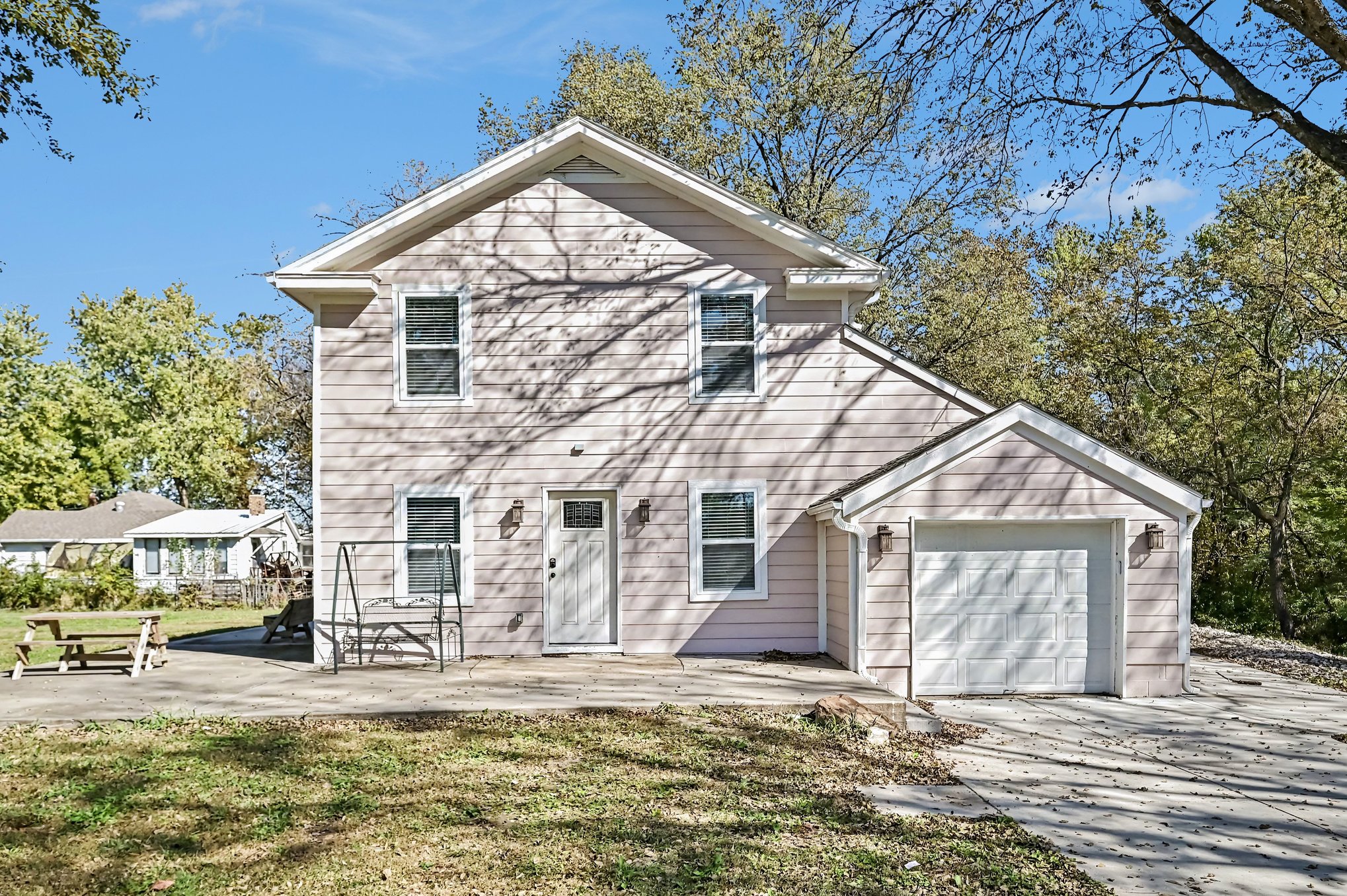 Front of the two-story home with attached one-car garage and concrete patio