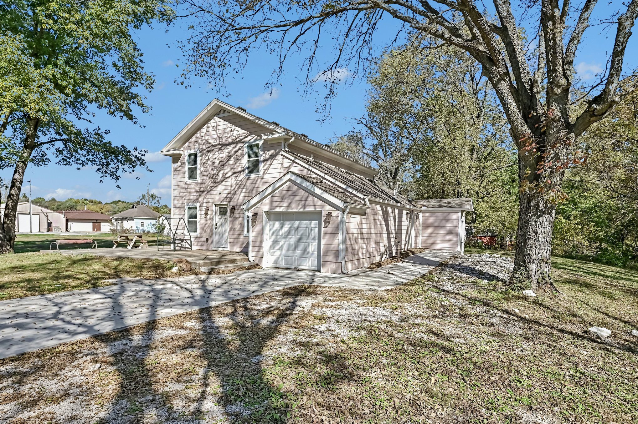 Side view showing concrete driveway, attached garage and mature trees