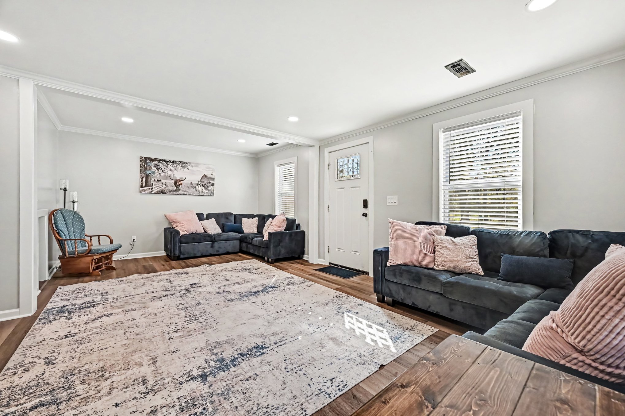 Spacious living room with two sectional sofas, luxury vinyl plank flooring, crown molding and recessed lighting