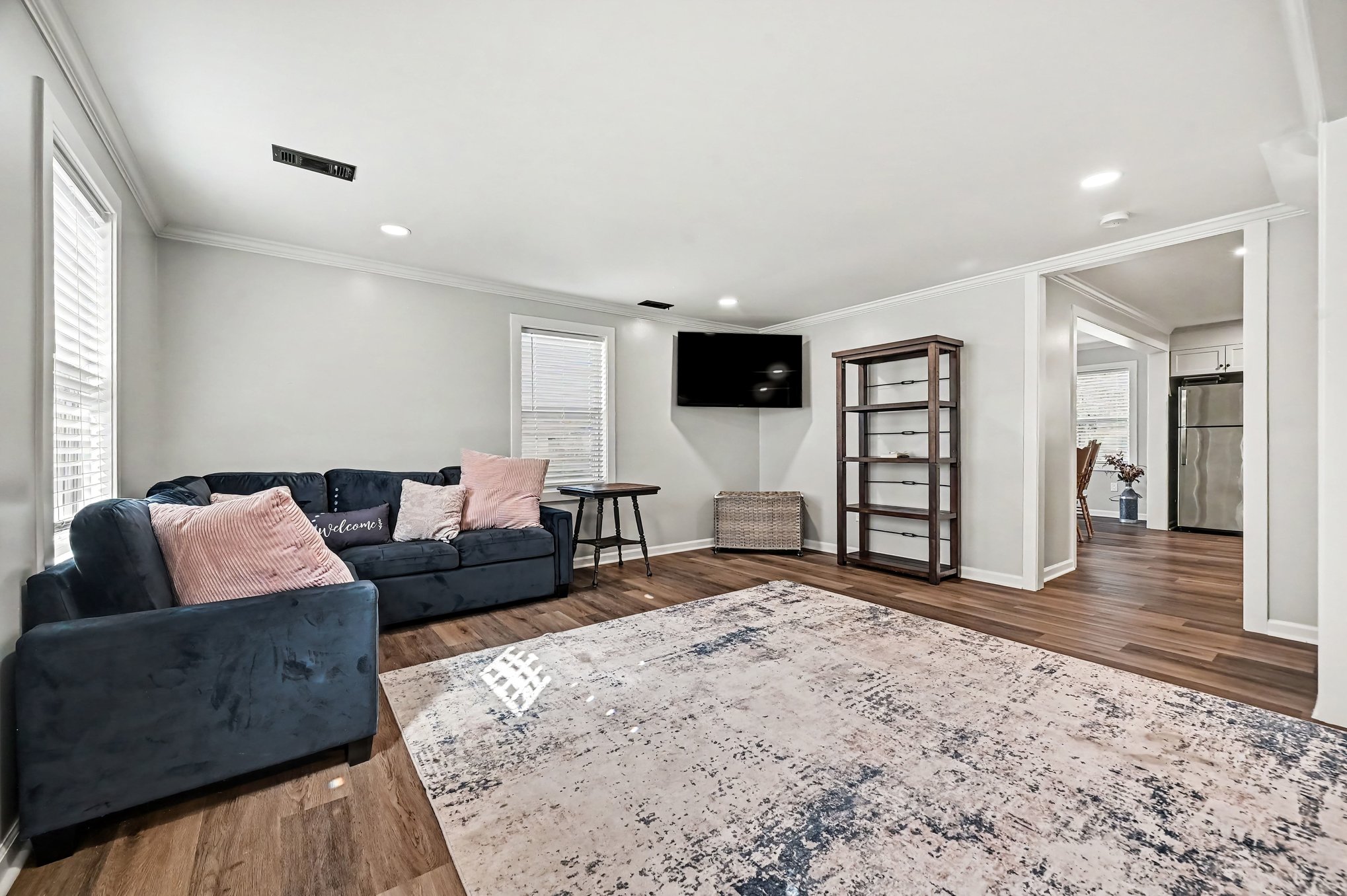 Living room toward kitchen, wall-mounted TV and open doorways