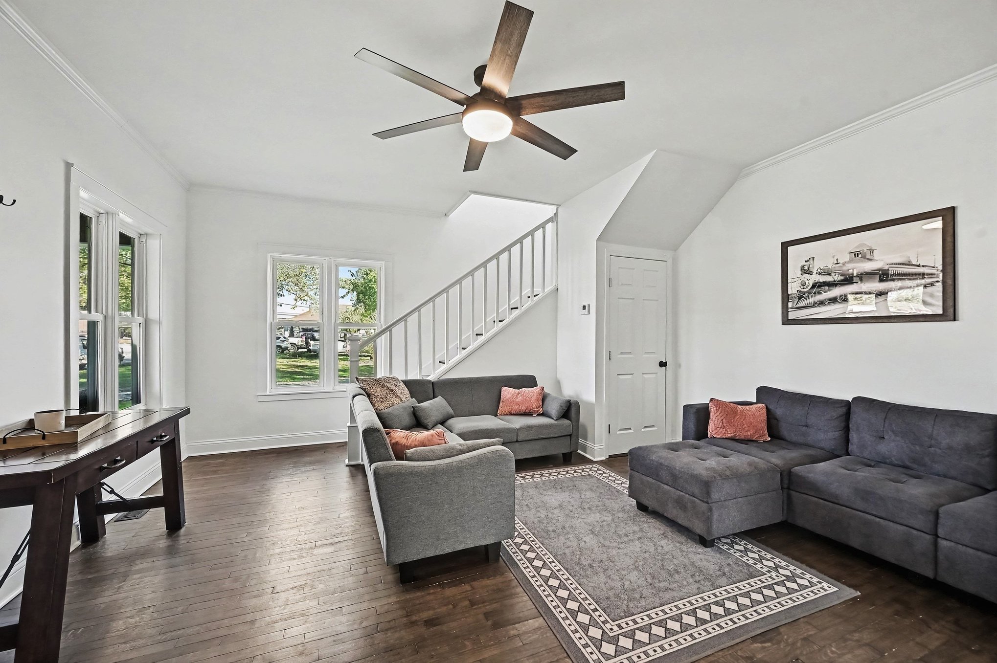 Living room with ceiling fan, crown molding and front windows