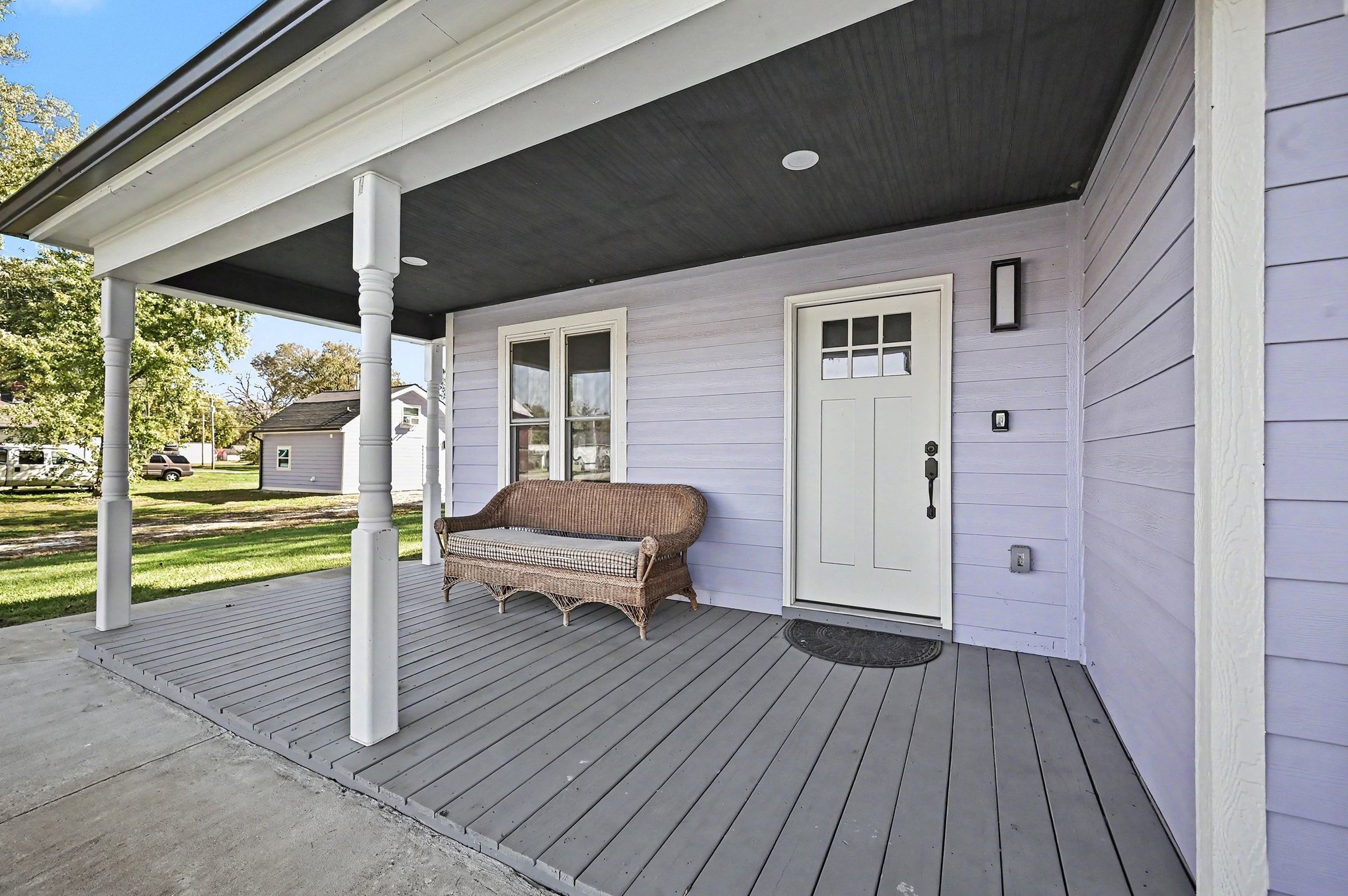 Covered front porch with wicker settee and craftsman entry door