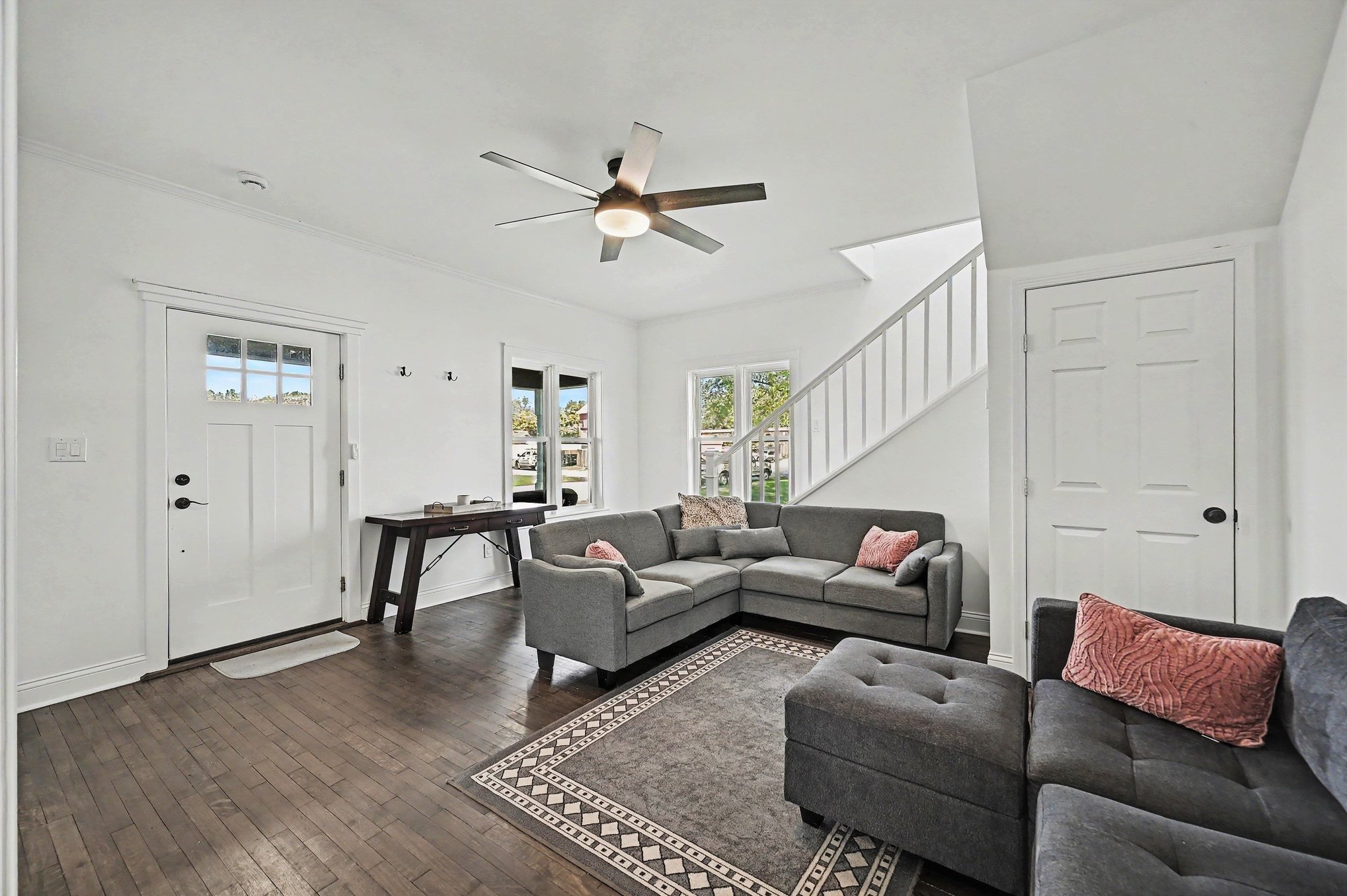 Main house living room with hardwood floors, sectional seating and staircase