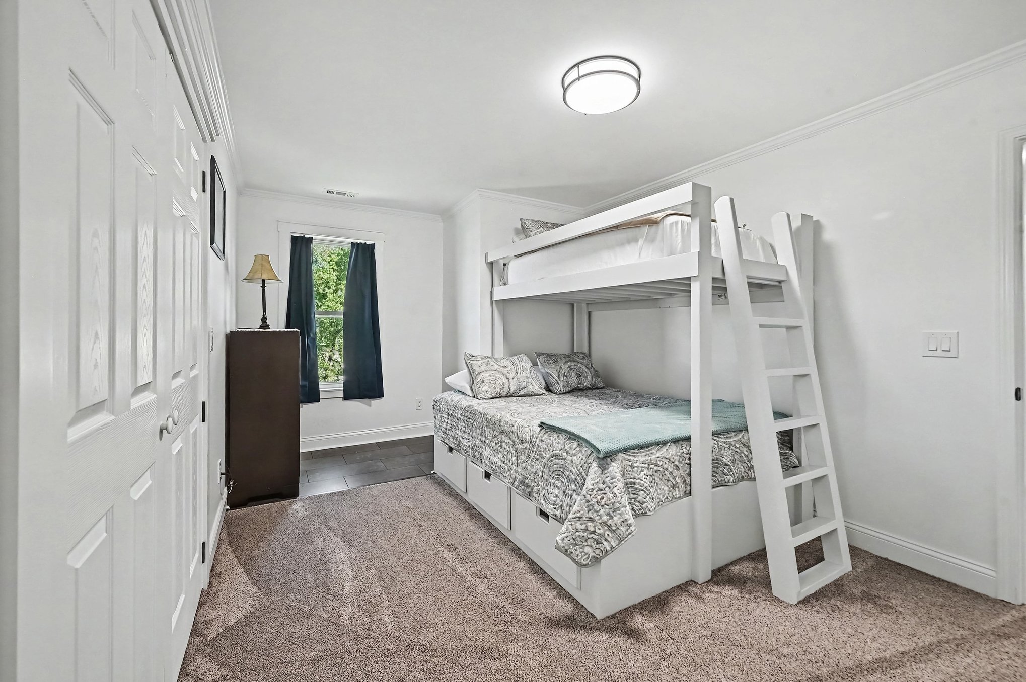 Upstairs bedroom with custom white built-in bunk bed, storage drawers and window