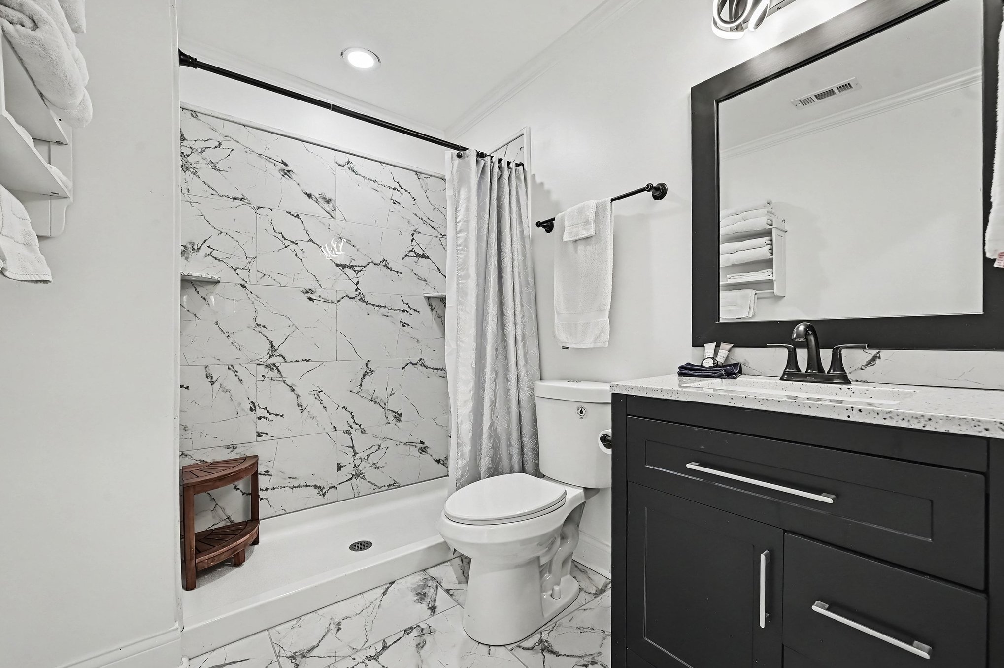 Upstairs bathroom with marble-look tiled shower and black vanity