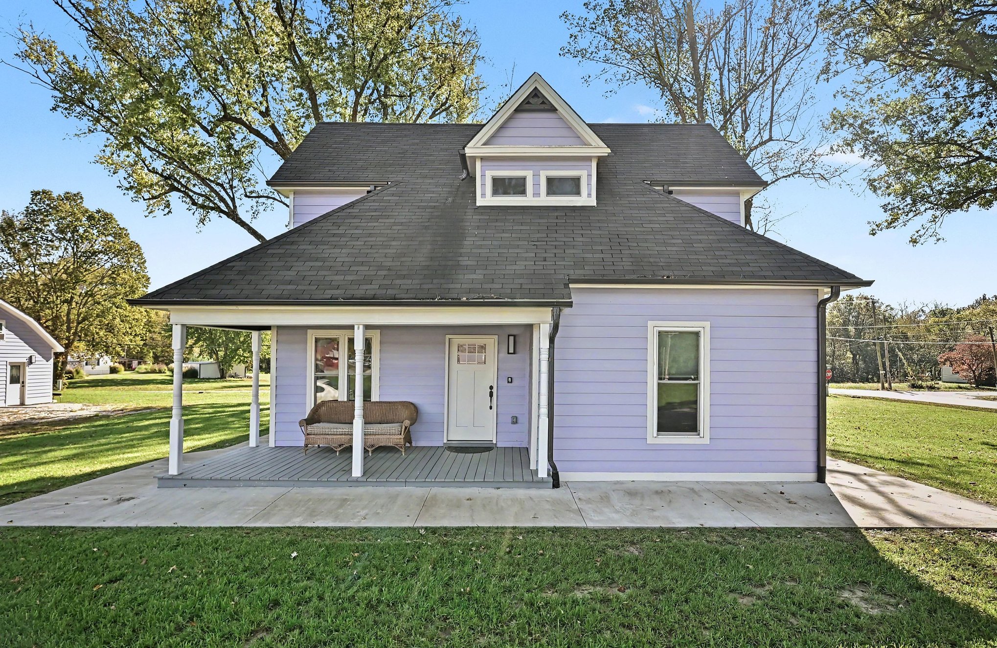 Front of the renovated farmhouse with covered porch and Victorian dormer