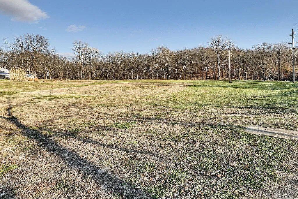 Wide open yard bordered by mature trees