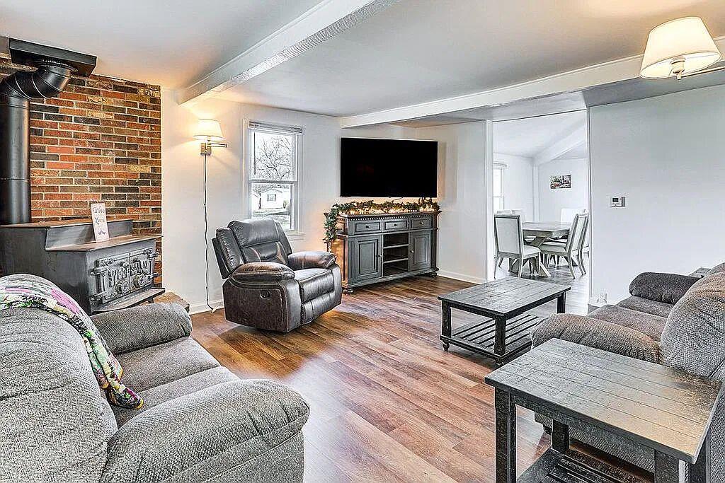 Living room with cast-iron wood-burning stove, exposed brick wall, wood-look floors and recliner seating