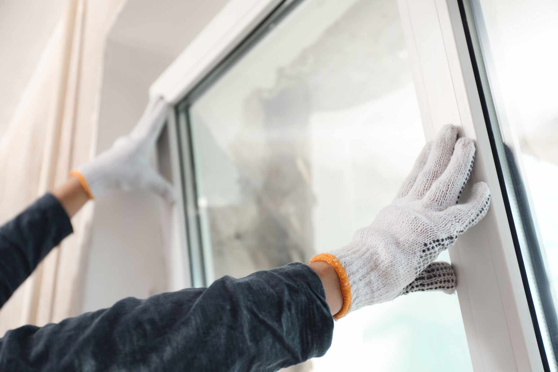 a person wearing gloves and holding a window