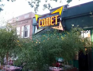 alt="A family enjoying pizza and ping pong at Comet Ping Pong, a popular and unique restaurant near Chevy Chase, MD."