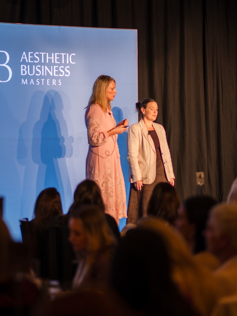 Kelly and Alicia on stage in front of a seated audience