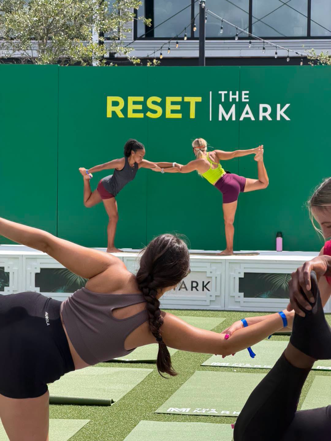 Jenny on stage leading a balance pose at a corporate wellness event, participants following along in the foreground