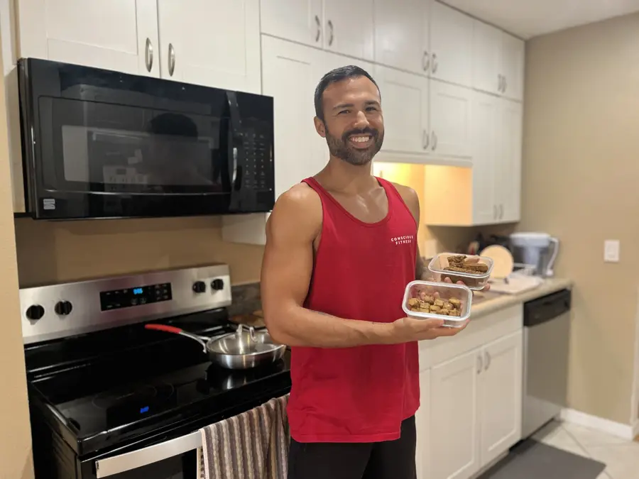 Bryan in his kitchen holding prepped high-protein meals