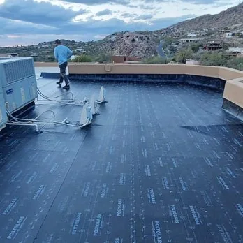 Base sheet laid out across a low-slope roof, crew still on it