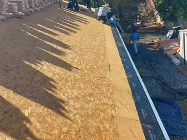 Bare roof deck with tarps spread across the ground below