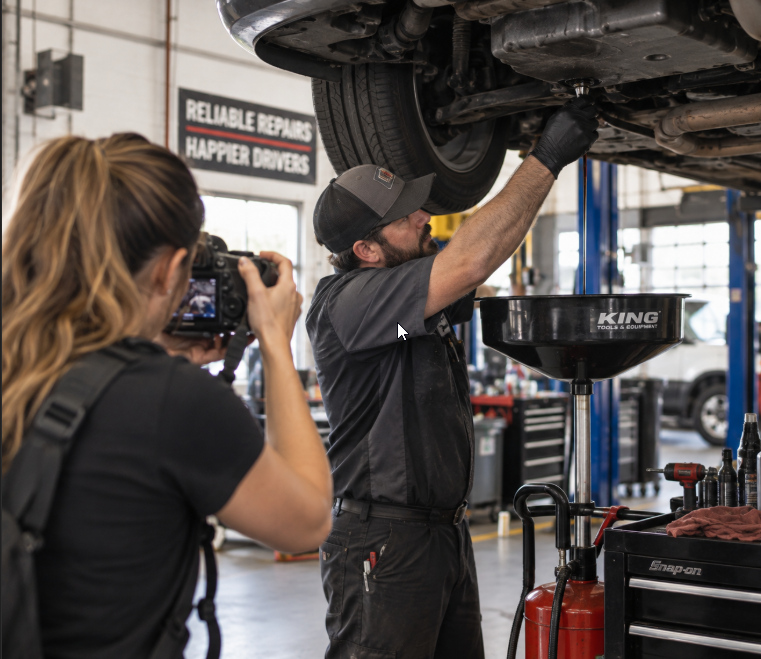 Photographer recording a technician working under a vehicle